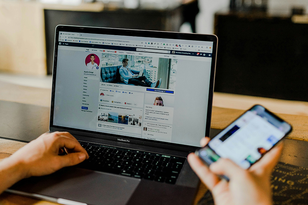 Person using a laptop and smartphone to manage online content and social media, representing digital marketing services focused on improving online presence and audience engagement