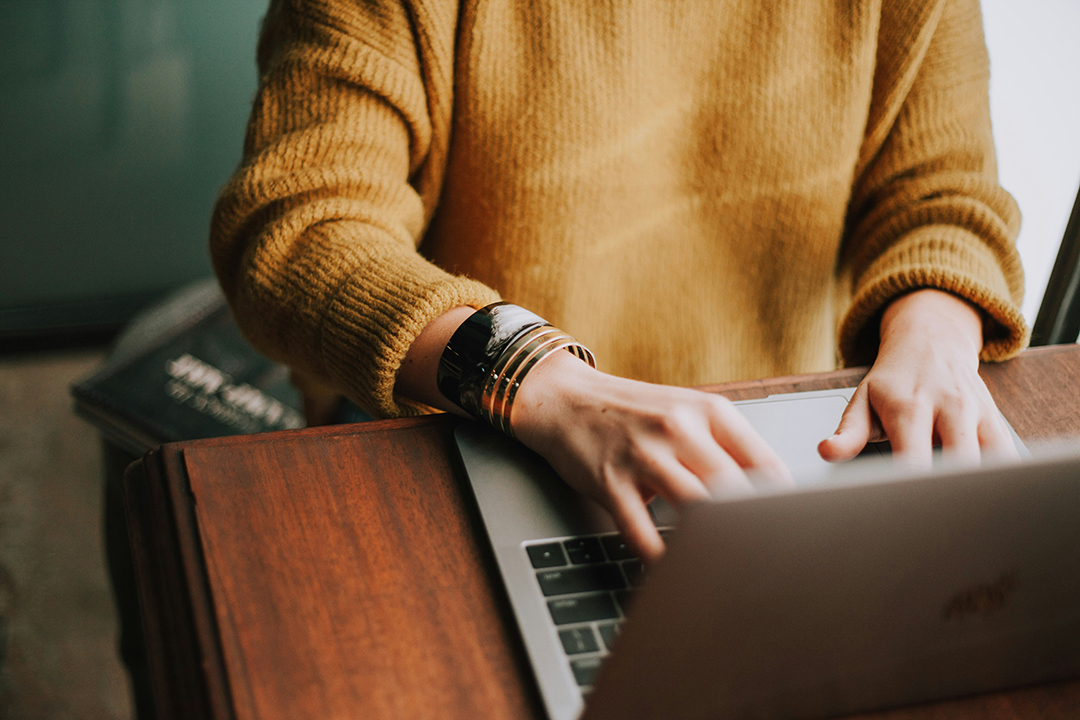 Close-up of a person typing on a laptop at a desk, symbolizing focused digital work and business growth through online strategy and marketing support