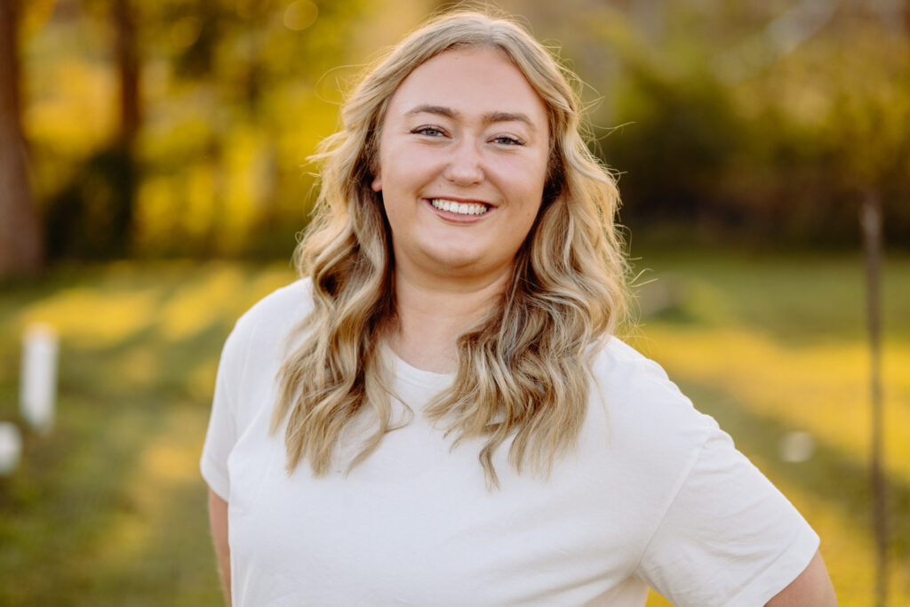young blonde woman in the outdoors with a confident smile who is a marketing strategist professional
